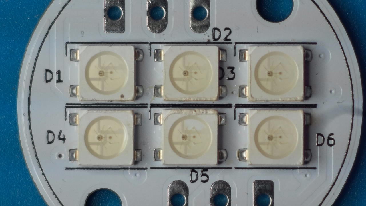 Close-up view of a circular PCB with 6 addressable LED's soldered on